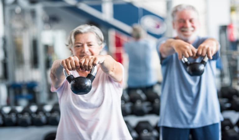 Two older people working out in the gym.