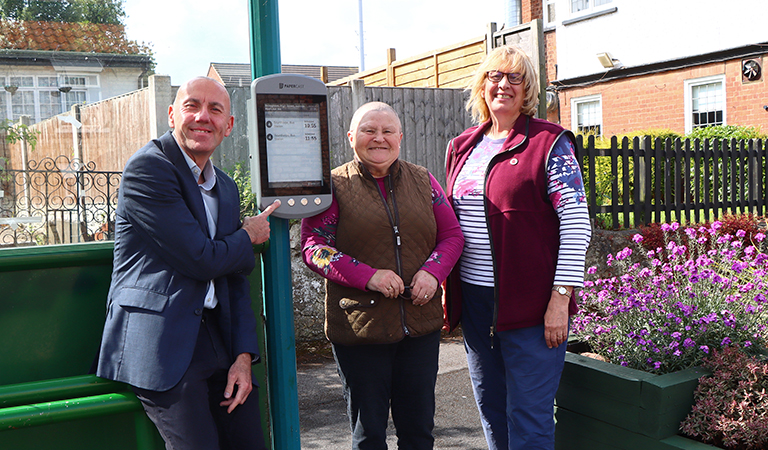 Cllr Rob Waltham, Cllr Carol Ross and and Cllr Janet Lee looking a new digital bus display in Broughton.