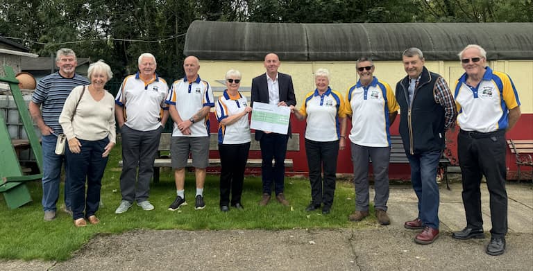A lineup of bowls club members with Rob Waltham holding a large cheque