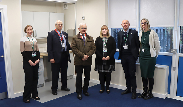 A lineup of six people inside a blue and white classroom