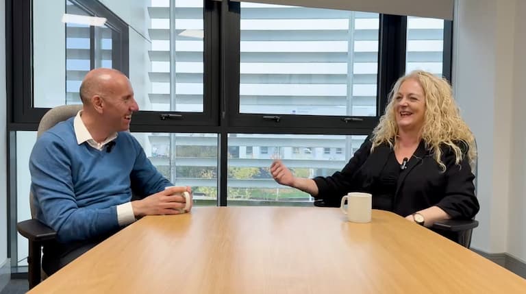 Rob Waltham interviewing Sue Rands at a table with a window behind them