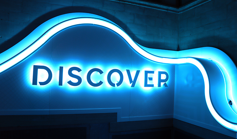 Blue neon sign saying 'Discover'