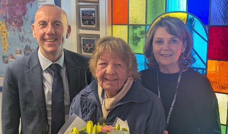 Three people standing in front of a coloured stained glass window